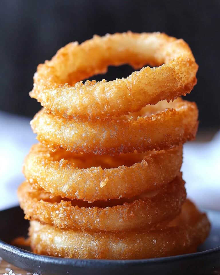 Crispy homemade onion rings stacked on a black bowl for air fryer recipe.