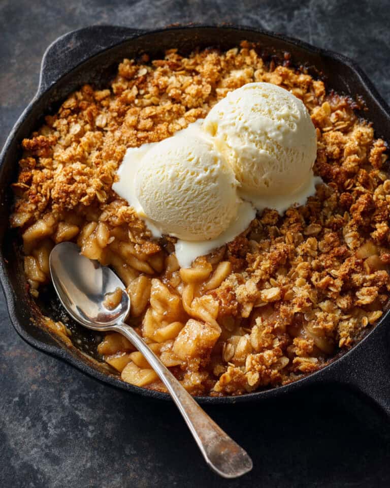 Warm apple crumble with vanilla ice cream in a cast iron skillet for easy freezer-to-air-fryer dessert.