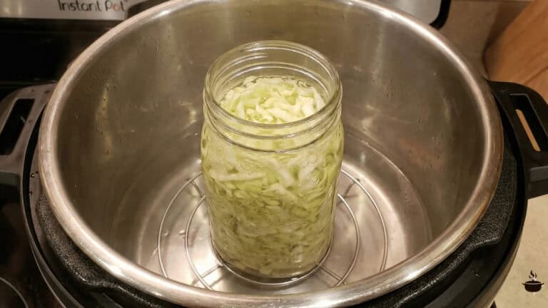 A mason jar of fermenting sauerkraut sitting inside an Instant Pot on the yogurt setting.